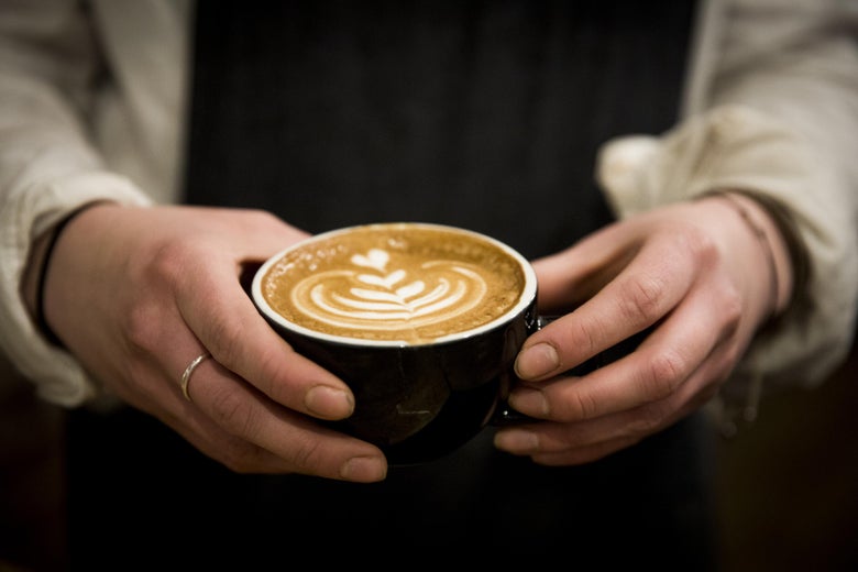 Hands holding a cafe latte.